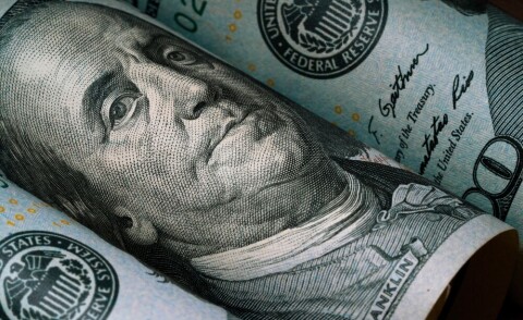 Close-up of Benjamin Franklin on a rolled US $100 banknote.