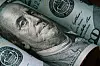 Close-up of Benjamin Franklin on a rolled US $100 banknote.